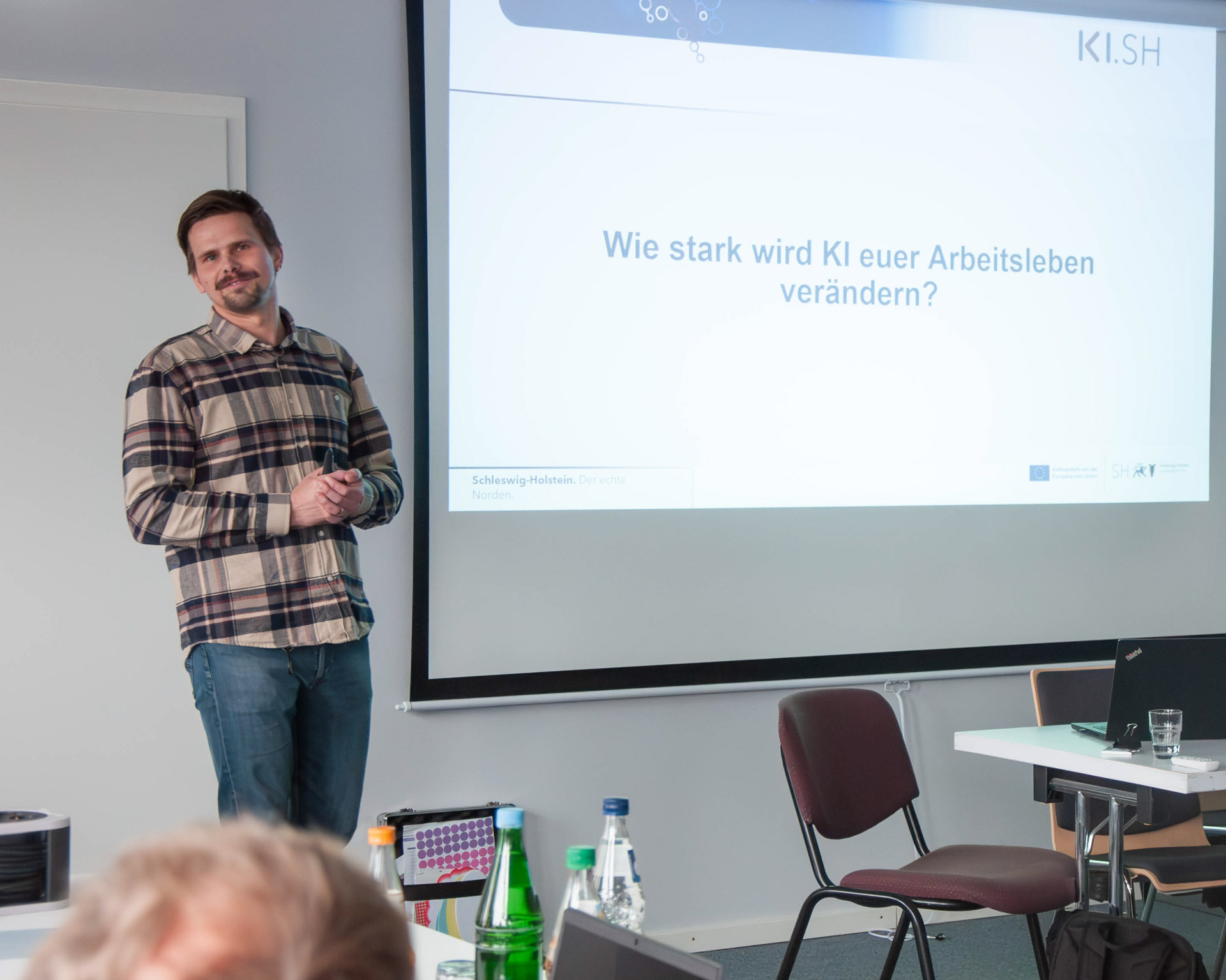 Nils Lockmann steht vor eine Beamerleinwand
